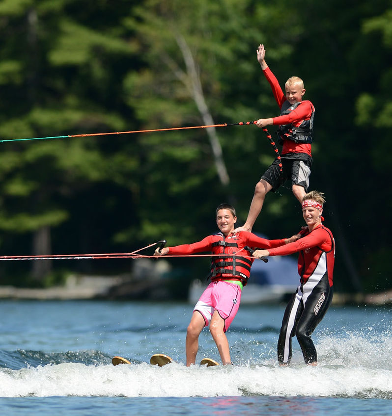 Campers and staff members form a tower on the lake