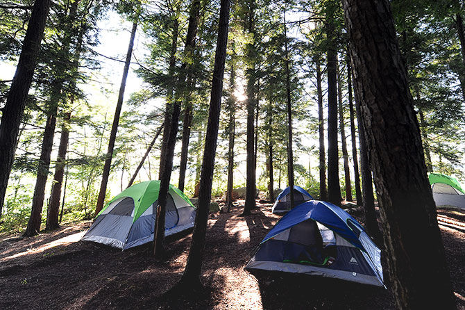 Tents sit in the woods of Camp Manitou's island camp site