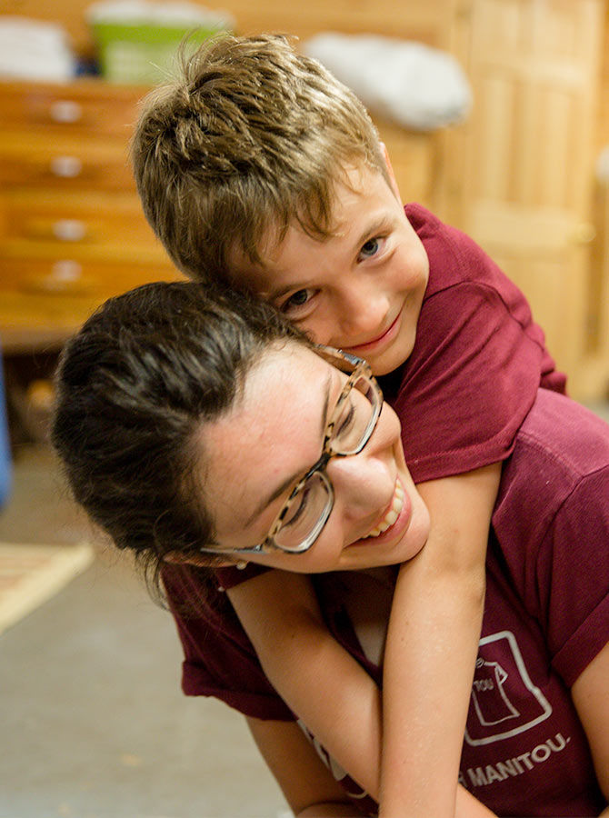A camper at Manitou hugs his counselor
